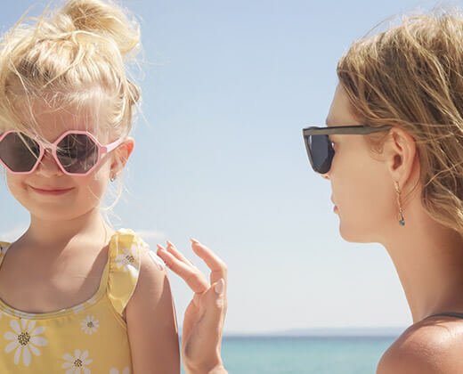 kobieta smaruje córkę kremem z filtrem dla dzieci