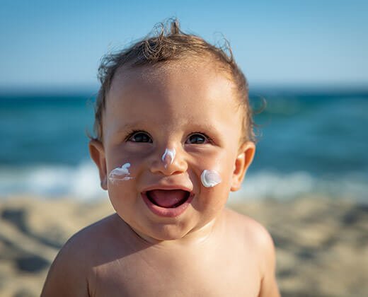 Niemowlę na plaży z twarzą nasmarowaną kremem z filtrem