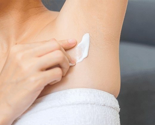 Kobieta aplikuje krem na swędzenie pod pachami