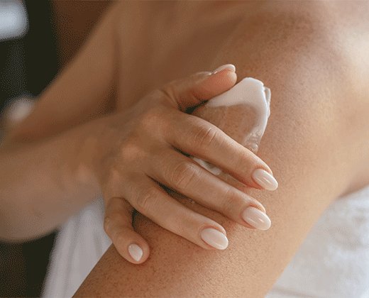 Kobieta aplikująca na ramiona krem łagodzący podrażnienia