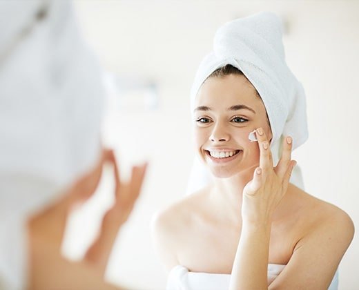 Młoda kobieta aplikuje krem na pokrzywkę na twarzy